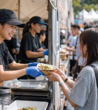 大型イベントのフードブースでスタッフが完成した料理を来場者へ素早く受け渡している様子