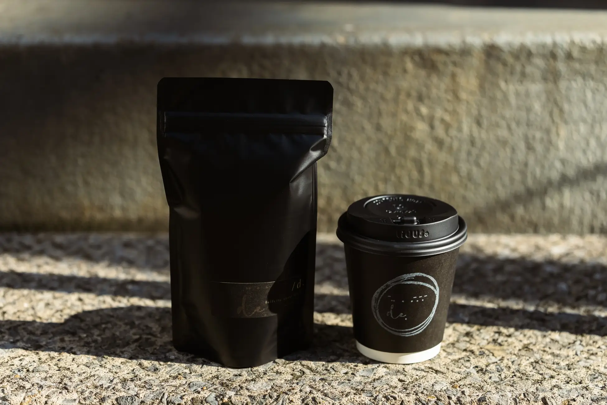 de.coffee roastersのコーヒー豆パッケージとロゴ入りテイクアウトカップ