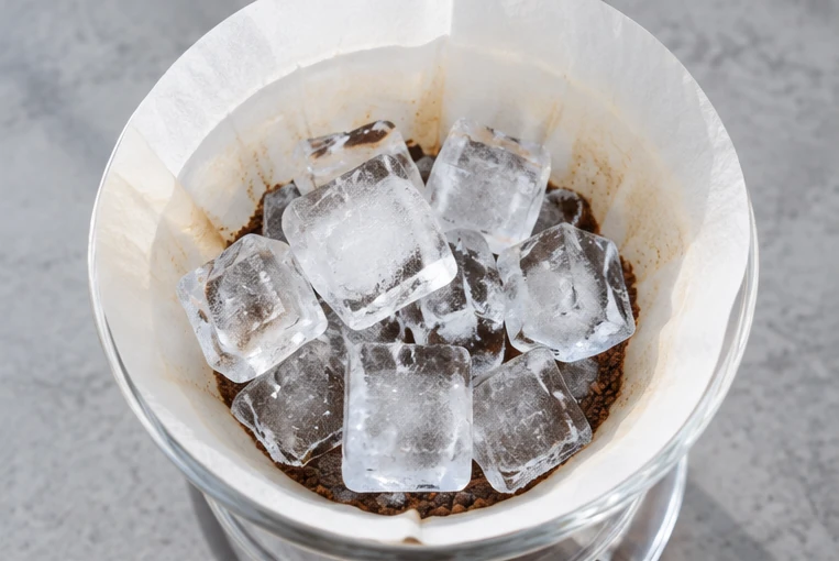 コーヒー粉の上に透明な氷を置いたドリッパーを上から見た抽出イメージ