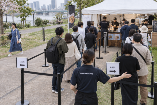 会計待ち列と通行スペースを分けて案内するスタッフ