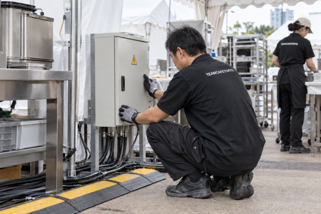 仮設分電盤と配線経路を確認するスタッフ